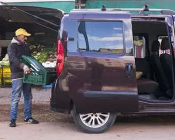 vendeur des légumes mit sa marchandise dans sa voiture